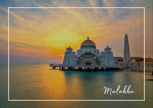 Die Moschee von Melaka steht ruhig im Wasser und wird von einem warmen Sonnenuntergang in Orange, Gold und Rosa eingerahmt. Das spiegelnde Meer, die langen Uferlinien und der weite Himmel lassen das Bauwerk besonders markant wirken. Im Hintergrund zeichnet sich der schlanke Minarettturm klar gegen den Abendhimmel ab.