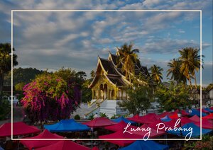  Wat Xieng Thong erhebt sich inmitten von Palmen, bunten Blumen und einer ruhigen, tropischen Landschaft und wirkt dabei besonders prachtvoll. Das goldene Gebäude mit seinen geschwungenen Dächern verleiht der Szene eine feierliche und zugleich friedliche Atmosphäre.