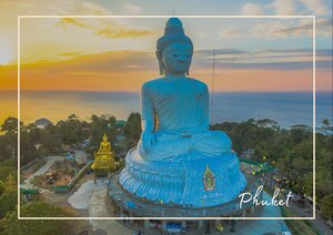 In Phuket erhebt sich die große Buddha-Statue ruhig über die Landschaft und scheint im warmen Licht des Abends fast zu schweben. Unter ihr breitet sich eine weiche, grüne Inselkulisse aus, während der Himmel in Gold, Orange und sanftem Blau leuchtet. Die Szene wirkt dadurch würdevoll, friedlich und zugleich eindrucksvoll weit.