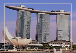 Die Marina Bay in Singapur zeigt sich mit ihrer modernen Skyline und den markanten Gebäuden als eindrucksvolle Stadtkulisse. Vor den gläsernen Hochhäusern setzen die hellen Formen im Vordergrund und die klaren Linien der Architektur einen starken Kontrast, der den Ort sofort wiedererkennbar macht.