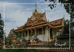 Ein kunstvoll verzierter Tempel mit mehrstufigem Dach steht inmitten eines gepflegten Gartens und wird von Bäumen umrahmt. Die traditionelle Architektur mit ihren goldenen und roten Details hebt sich vor dem bewölkten Himmel besonders hervor.