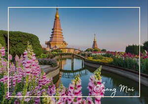 Chiang Mai zeigt sich hier in einer fast malerischen Symmetrie: ein goldener Tempelpunkt steigt über dem Wasser auf und spiegelt sich ruhig im langen Kanal darunter. Rundherum breiten sich pinke Blüten und üppiges Grün aus, sodass die Anlage wie ein stiller Garten mitten in der Stadt wirkt. Der helle Himmel und das weiche Licht geben dem Bild eine friedliche, warme Stimmung, die Chiang Mai besonders elegant erscheinen lässt.