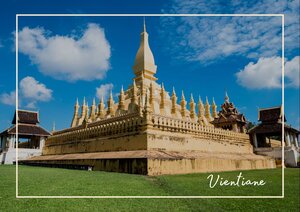 Die Pha That Luang erhebt sich vor einem strahlend blauen Himmel mit ihrer goldenen, eindrucksvollen Spitze und den vielen filigranen Details. Der grüne Rasen und die helle Fassade lassen das Bauwerk ruhig, würdevoll und besonders majestätisch wirken.