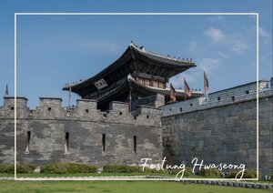 Die Festung in Fenghuang zeigt eine lange, graue Steinmauer mit kleinen, schmalen Öffnungen und einem breiten Wehrgang, der sich entlang der Anlage zieht. Dahinter erhebt sich ein traditionelles Torhaus mit geschwungenem, dunkel gedecktem Dach und mehreren Ebenen, das mit der massiven Mauer einen starken Kontrast bildet.