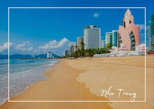 Nha Trang zeigt hier seine entspannte Küstenseite: ein breiter Sandstrand, ruhiges Meer und eine Skyline aus modernen Gebäuden am Ufer. Im Vordergrund öffnet sich die lange Strandlinie, während sich rechts die markanten Häuser und der helle Bau deutlich gegen den blauen Himmel abheben. Dadurch wirkt die Szene freundlich, luftig und typisch für eine lebendige vietnamesische Küstenstadt.
