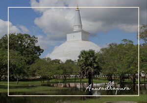 Im Zentrum des Bildes steht eine große weiße Stupa in Anuradhapura, Sri Lanka, deren runde Form und glatte Oberfläche sich deutlich vom Himmel abheben. Rundherum wachsen grüne Bäume und Büsche, und im Vordergrund führt eine parkähnliche Fläche mit Wegen und etwas Gras auf das Bauwerk zu. Über der Stupa liegt ein heller Himmel mit einzelnen Wolken, sodass die hellen Flächen des Gebäudes, das Grün der Umgebung und das Blau-Weiß des Himmels klar voneinander zu unterscheiden sind.