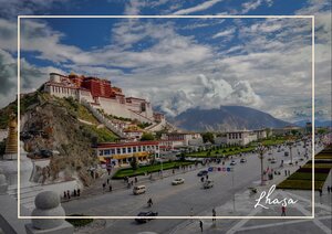 Lhasa in Tibet breitet sich hier am Fuß eines steilen Hangs aus, über dem der Potala-Palast wie eine majestätische Krone auf dem Berg thront. Im Vordergrund ziehen sich breite Straßen und einzelne Gebäude durch die Stadt, während die Berge dahinter den Horizont still einrahmen. Das Licht und der weite Himmel geben der Szene eine klare, eindrucksvolle Größe, die Lhasa zugleich lebendig und ehrwürdig wirken lässt.
