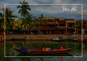 Hoi An zeigt hier seine ruhige Flussseite: Ein flaches Boot gleitet über das Wasser, während sich am Ufer alte Häuser, Palmen und das grüne Stadtbild spiegeln. Die Szene wirkt warm, lebendig und zugleich entspannt, mit einer sanften Mischung aus Alltag und historischem Charme. So bekommt Hoi An einen besonders malerischen und einladenden Eindruck.