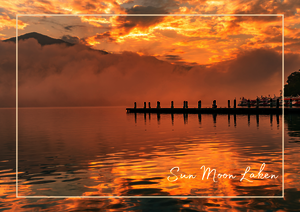 Der Sun Moon Lake liegt wie ein stiller Spiegel unter einem Himmel aus zartem Orange, Gold und feinen Wolkenstreifen. Das warme Licht legt sich sanft über das Wasser und lässt die Oberfläche in weichen Farben schimmern, fast als würde der See selbst den Abend glühen. Im Hintergrund verschwimmen die Berge im Dunst und geben der Szene eine ruhige, traumhafte Tiefe.